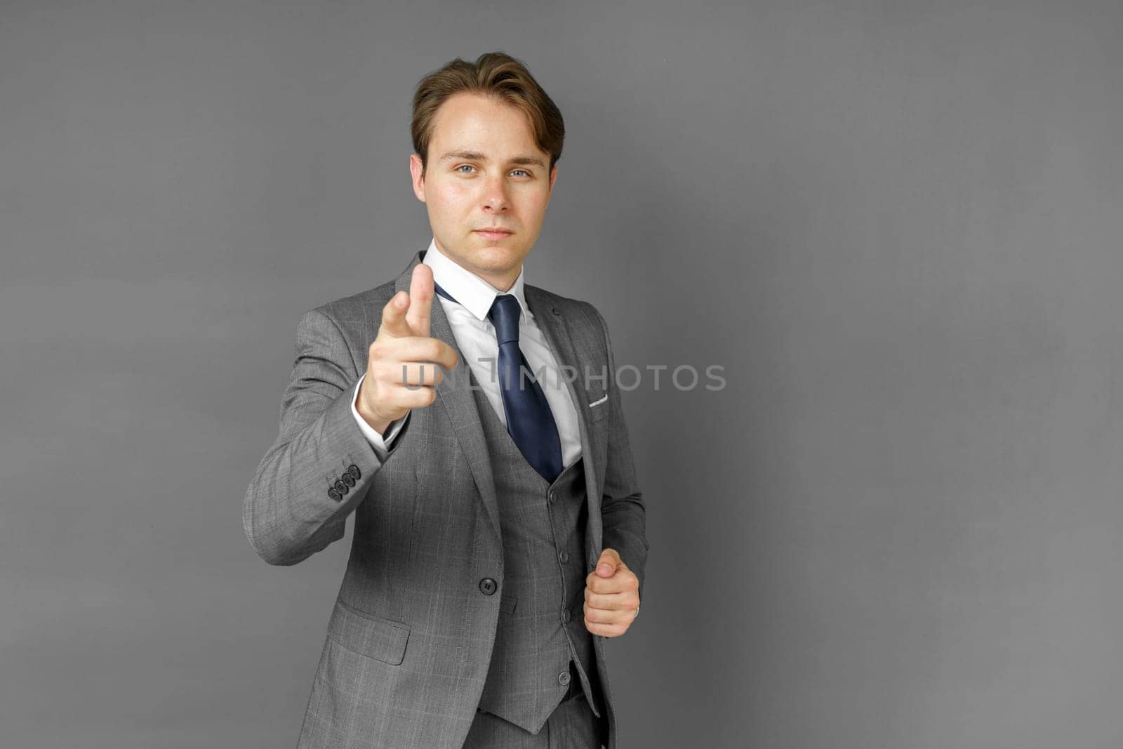 Portrait of a businessman in a suit that extended his hand forward. Gray background. Business and finance concept