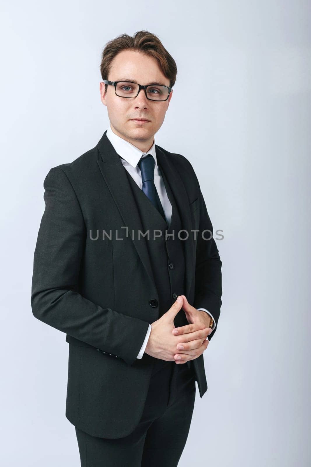 Business and finance concept. Portrait of a businessman in a black suit with glasses. Light background