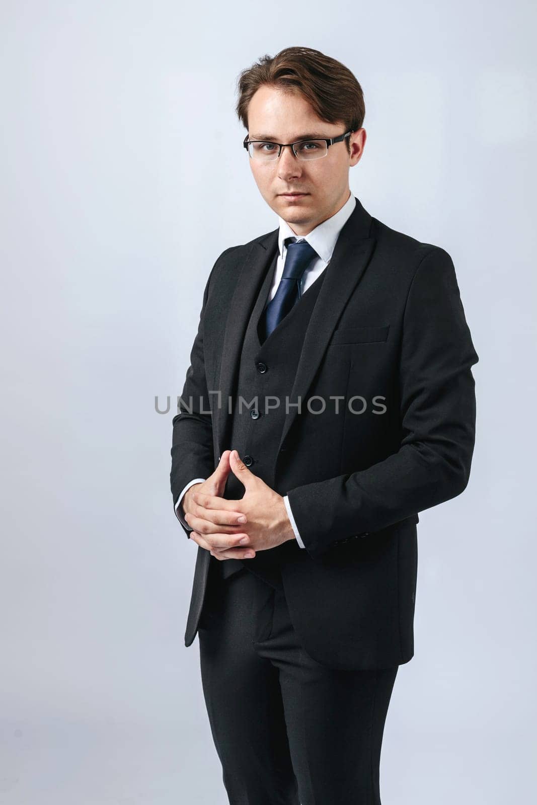 Business and finance concept. Portrait of a businessman in a black suit with glasses. Light background