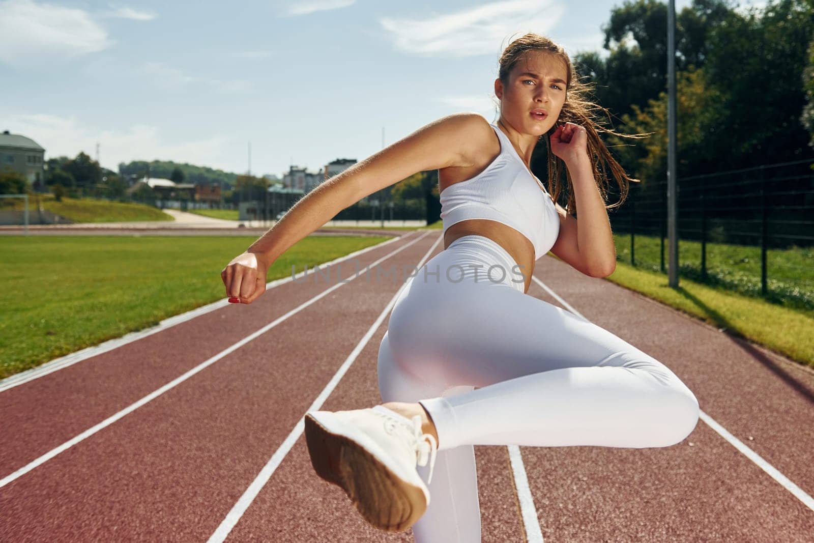 Practicing kickboxing. Young woman in sportive clothes is exercising outdoors.