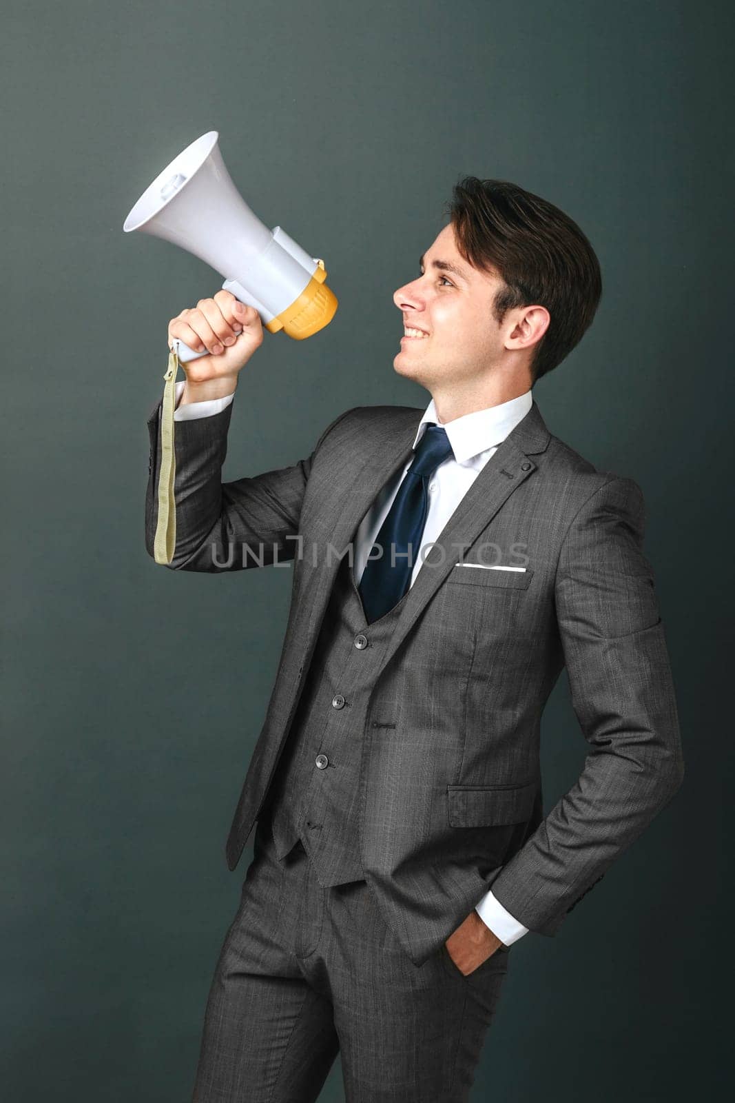 Business and finance concept. Portrait of a businessman who holds a megaphone in his hands. Light background