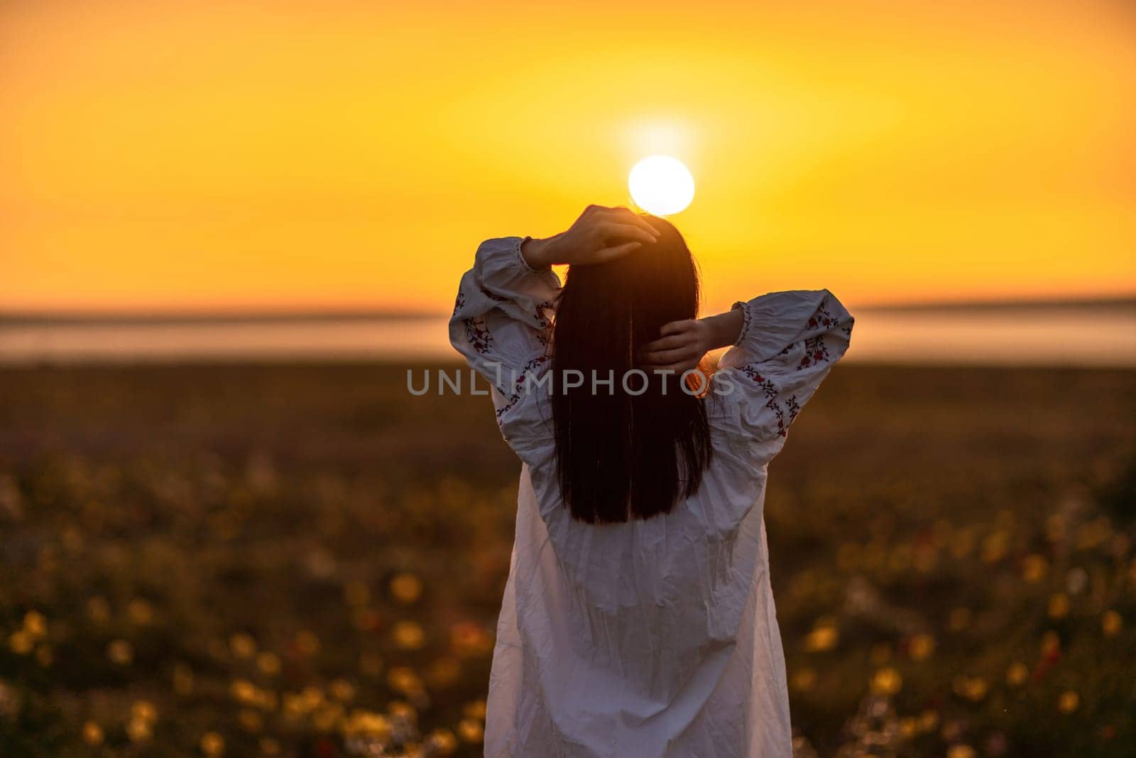 Woman back against sunset and wild tulip flowers, natural seasonal background. Multi-colored tulips Tulipa schrenkii in their natural habitat are listed in the Red Book