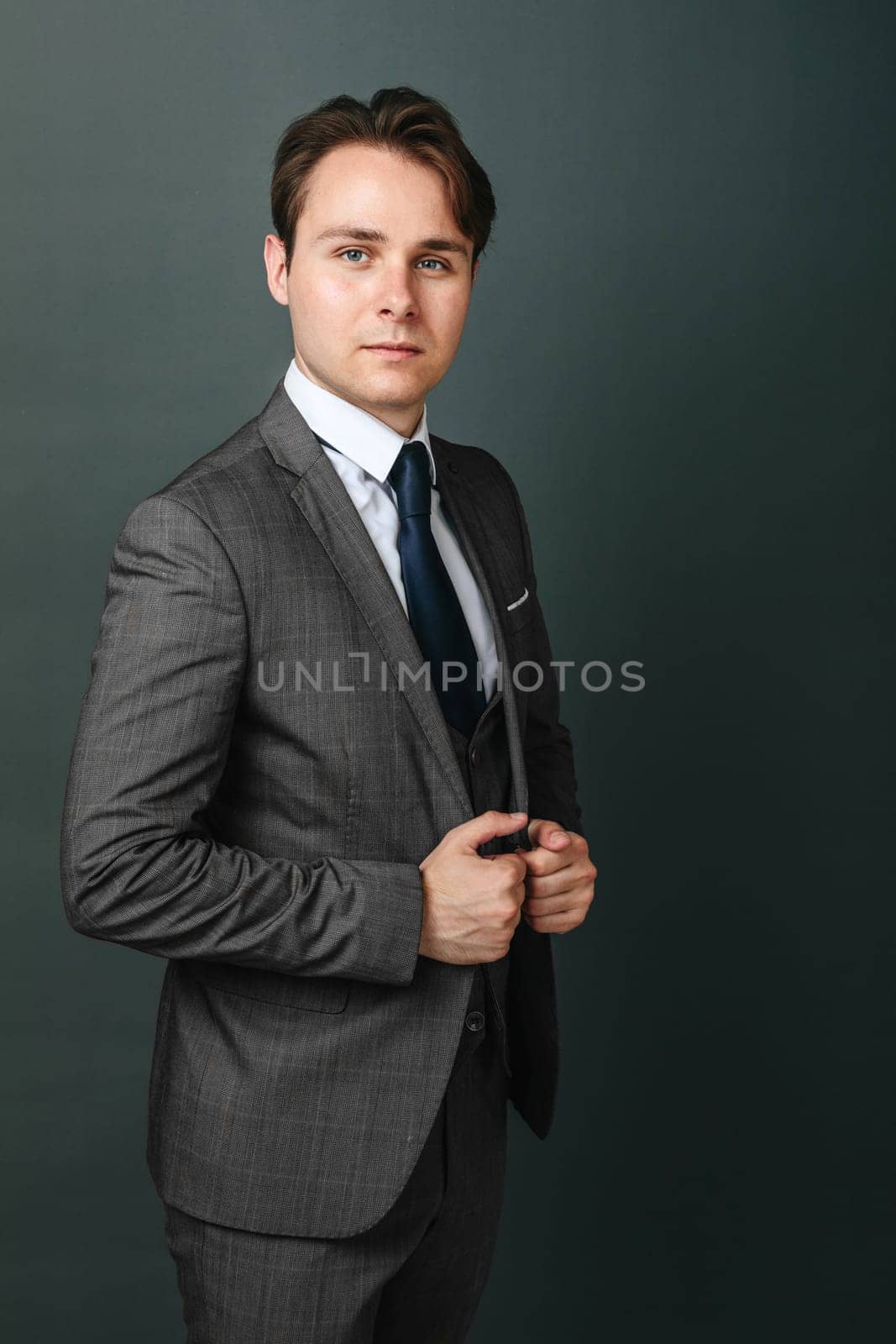 Business and finance concept. Portrait of a businessman who holds his suit with his hands and looks at the camera. Light background