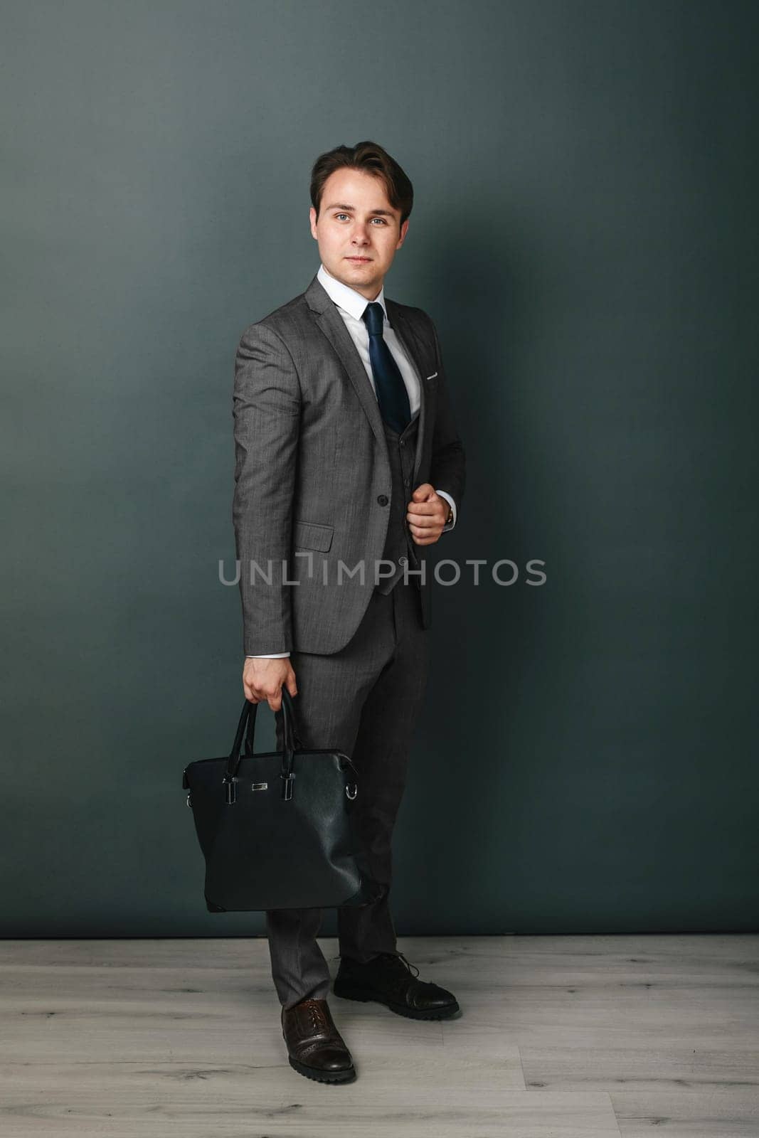 Business and finance concept. Portrait of a businessman who is holding a briefcase. Light background