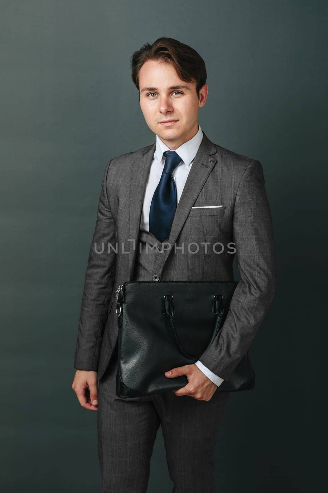 Business and finance concept. Portrait of a businessman who is holding a briefcase. Light background