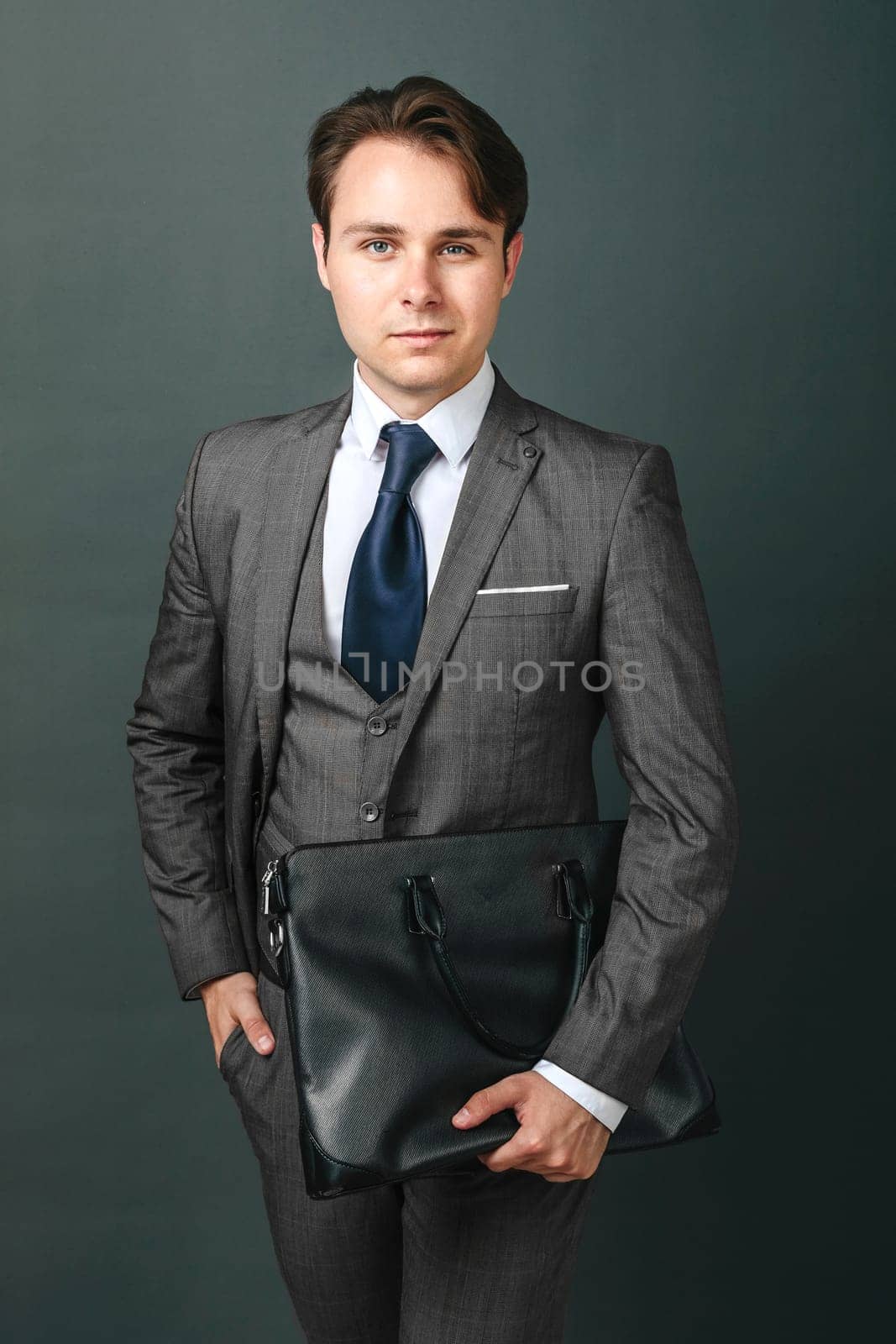 Business and finance concept. Portrait of a businessman who is holding a briefcase. Light background