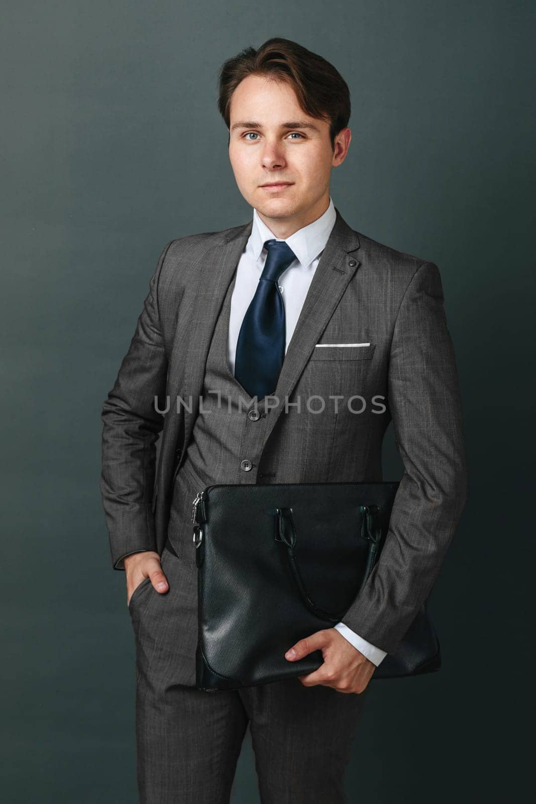 Business and finance concept. Portrait of a businessman who is holding a briefcase. Light background