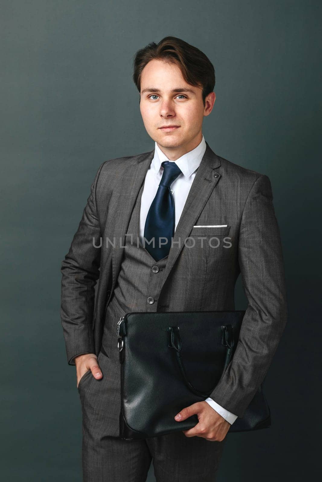 Business and finance concept. Portrait of a businessman who is holding a briefcase. Light background