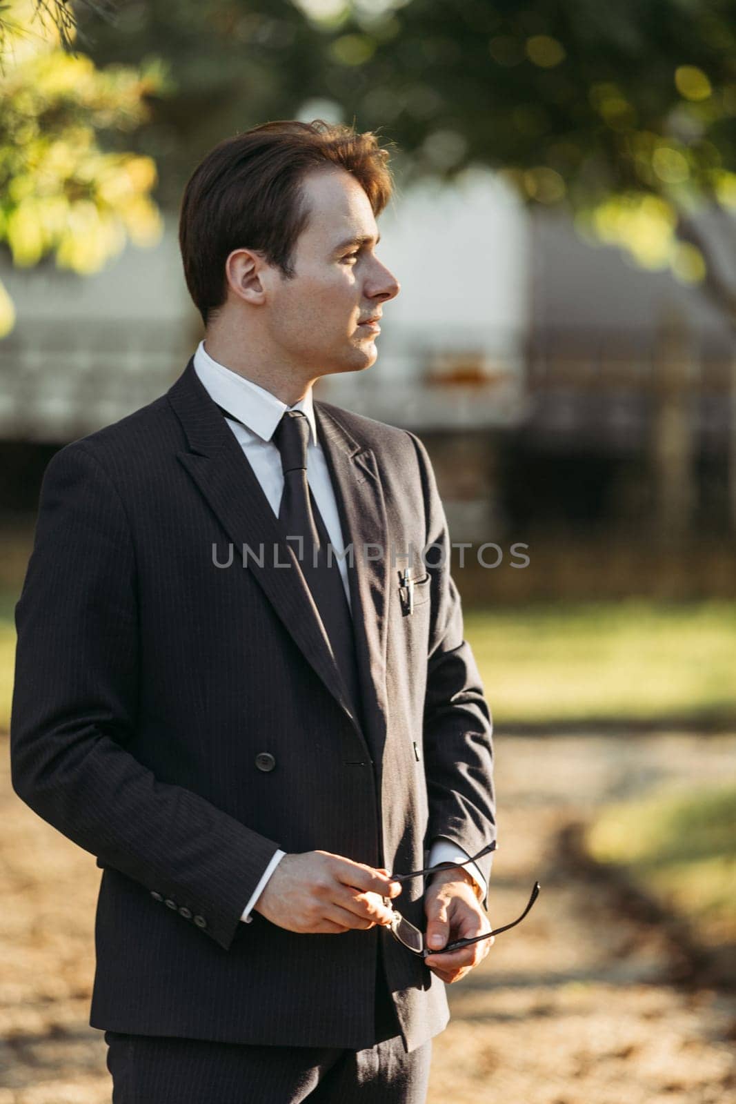 Business and finance concept. Portrait of a businessman holding glasses in his hands. In the park