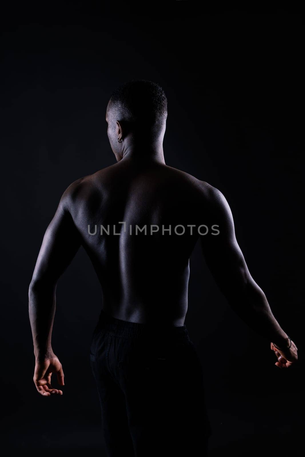 Portrait of athletic african american man topless, black background