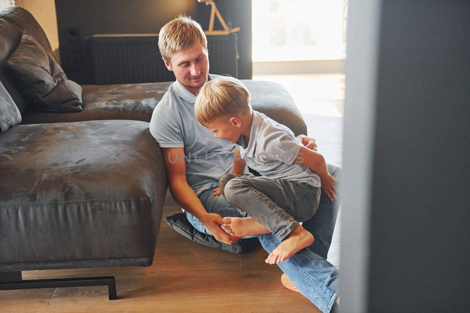 Having free time. Father and son is indoors at home together.
