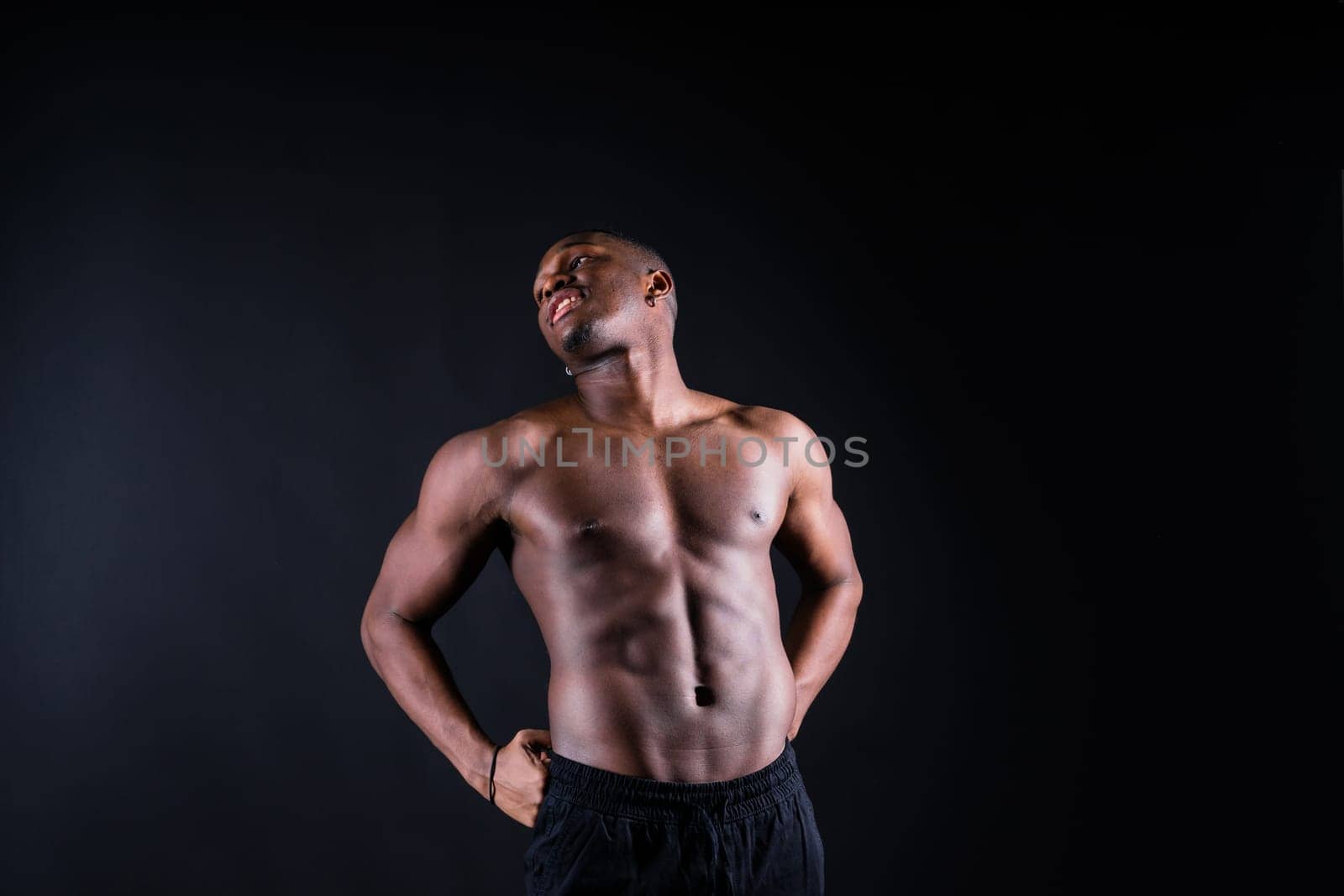 Portrait of athletic african american man topless, black background