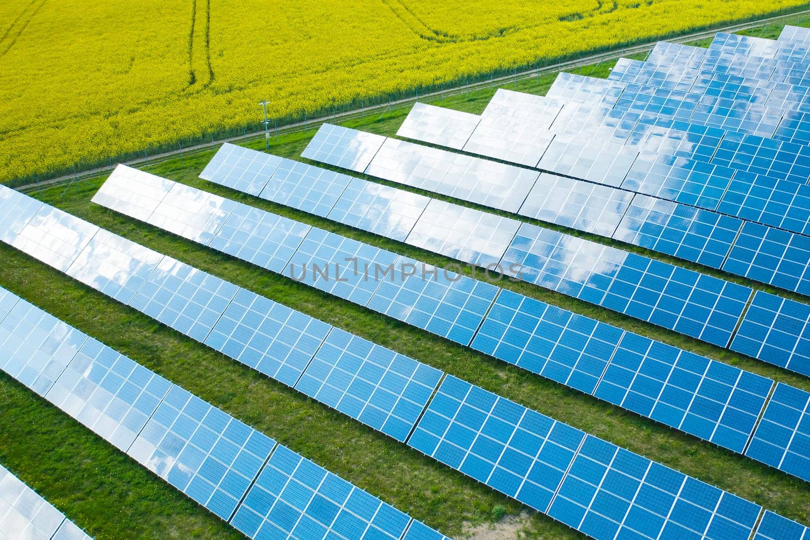 Long rows of sun panels built on green field. Innovative photovoltaic solar cells provide alternative energy at station aerial view