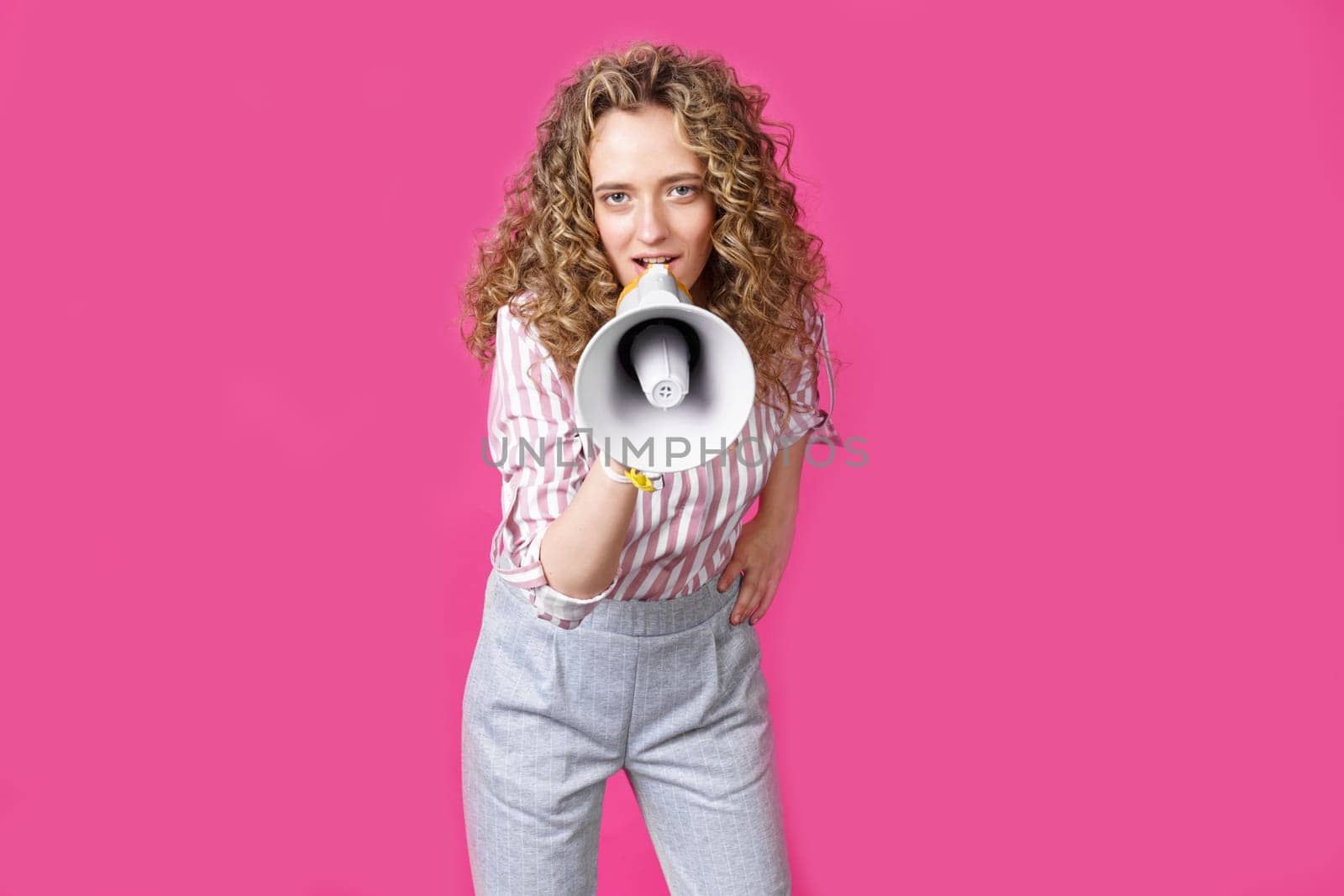 Young woman speaks into a megaphone. Isolated pink background. by Sd28DimoN_1976