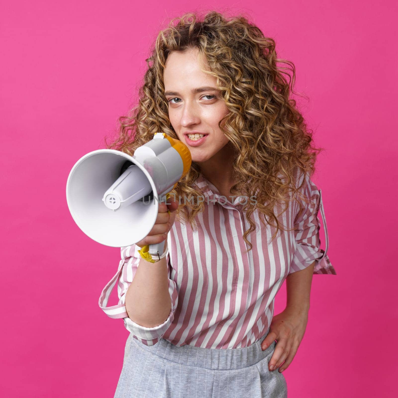 Young woman speaks into a megaphone. Isolated pink background. by Sd28DimoN_1976