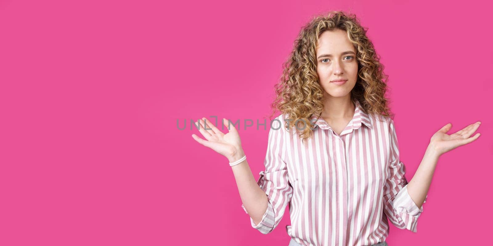 Portrait of a woman who holds her hands up, palms up. Isolated on a pink background.