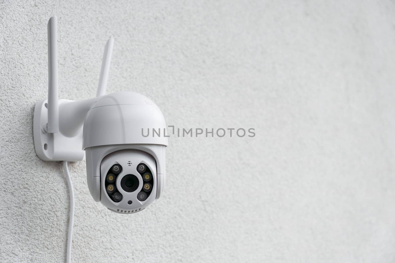 Round CCTV camera with antennas shoots video on the white wall. Digital equipment to record and broadcast real time video closeup