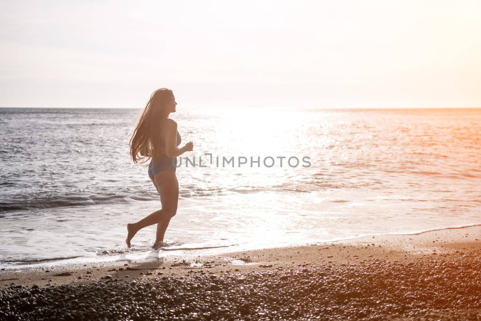 Running woman on a summer beach. A woman jogging on the beach at sunrise, with the soft light of the morning sun illuminating the sand and sea, evoking a sense of renewal, energy and health. by panophotograph