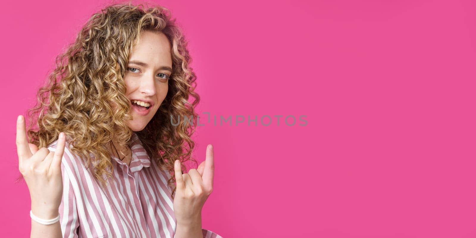 Close up photo of beautiful astonished lady fingers show V-sign toothy beaming smile. Isolated pink background