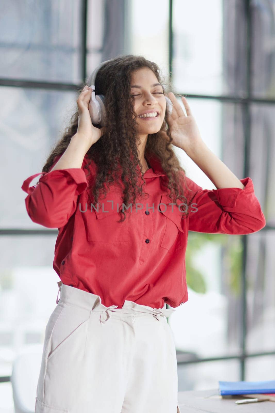 Young freelancer in headphone writing in notebook near laptop in office