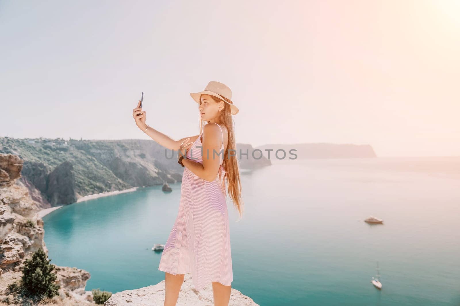 Digital nomad, Business woman working on laptop by the sea. Pretty lady typing on computer by the sea at sunset, makes a business transaction online from a distance. Freelance remote work on vacation