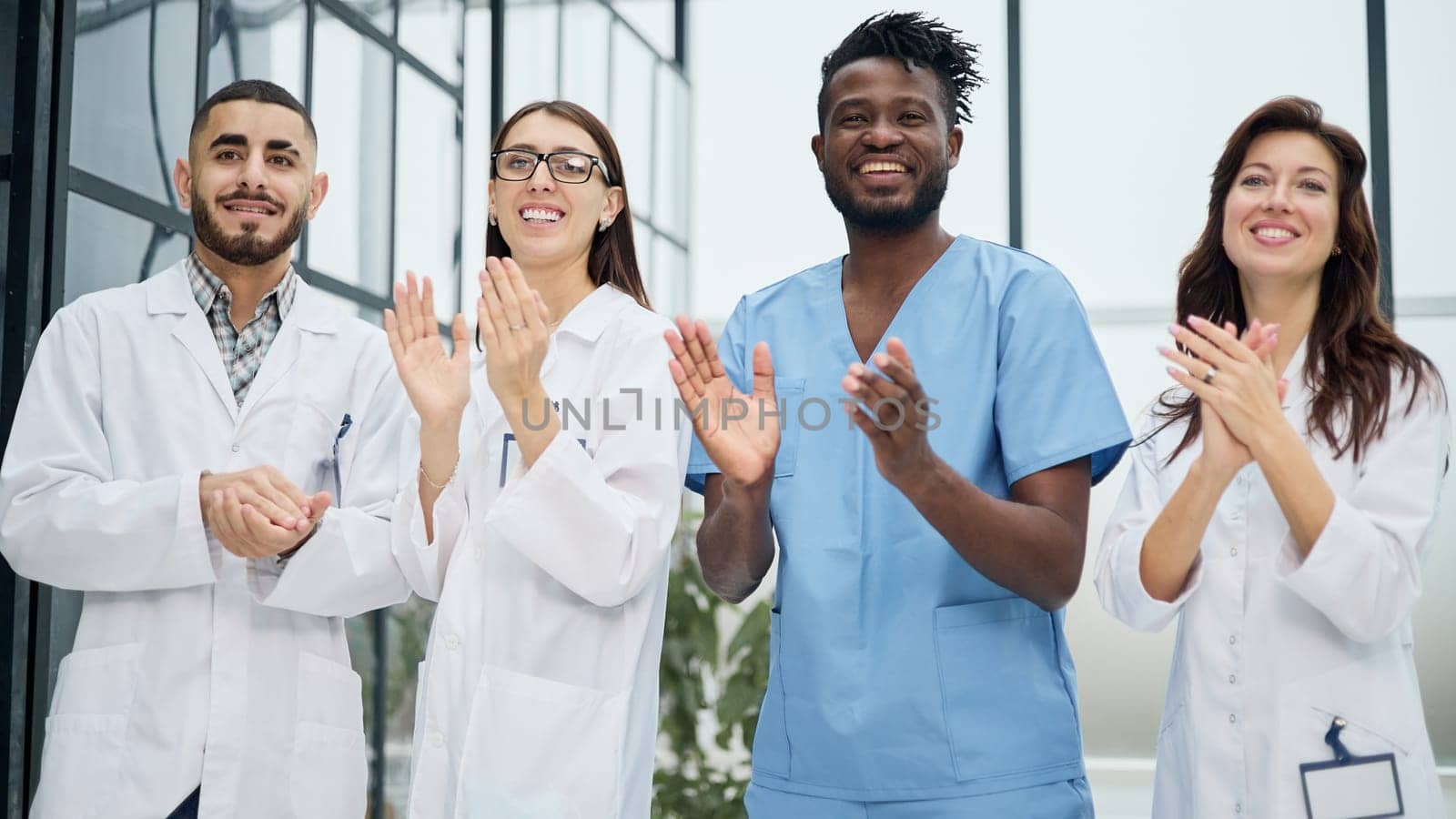 Successful team of different doctors clapping hands in hospital