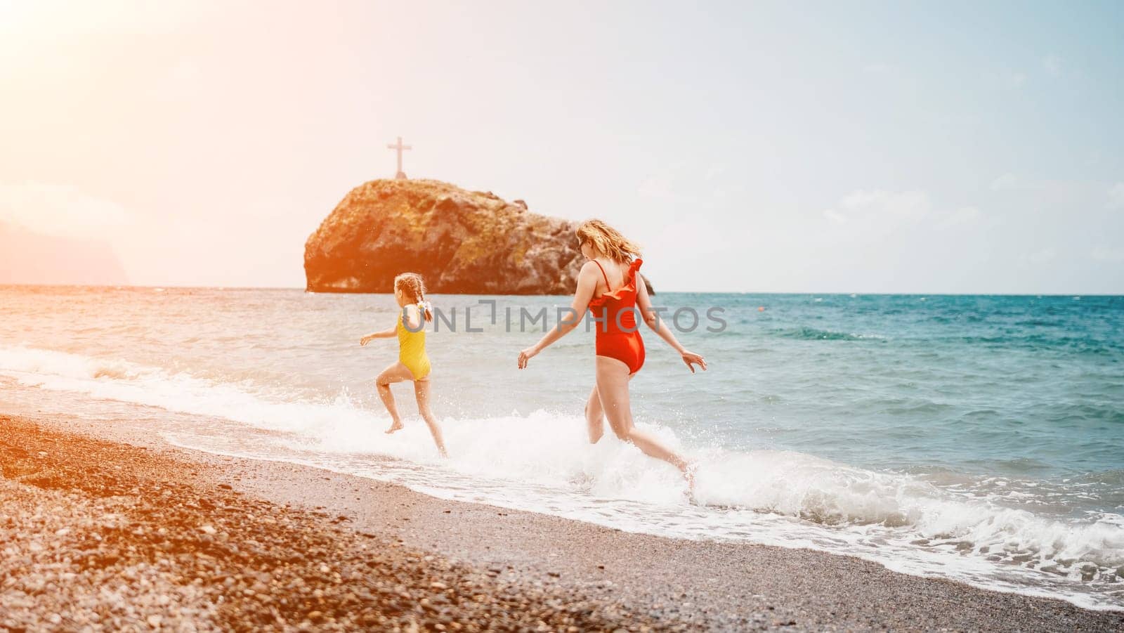 Happy loving family mother and daughter having fun together on the beach. Mum playing with her kid in holiday vacation next to the ocean - Family lifestyle and love concept.