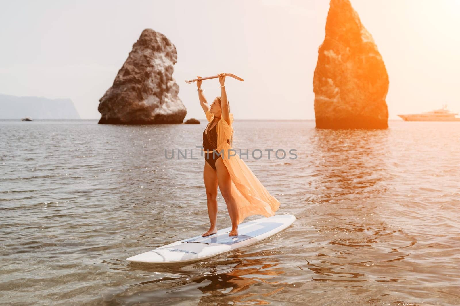 Close up shot of beautiful young caucasian woman with black hair and freckles looking at camera and smiling. Cute woman portrait in a pink bikini posing on a volcanic rock high above the sea