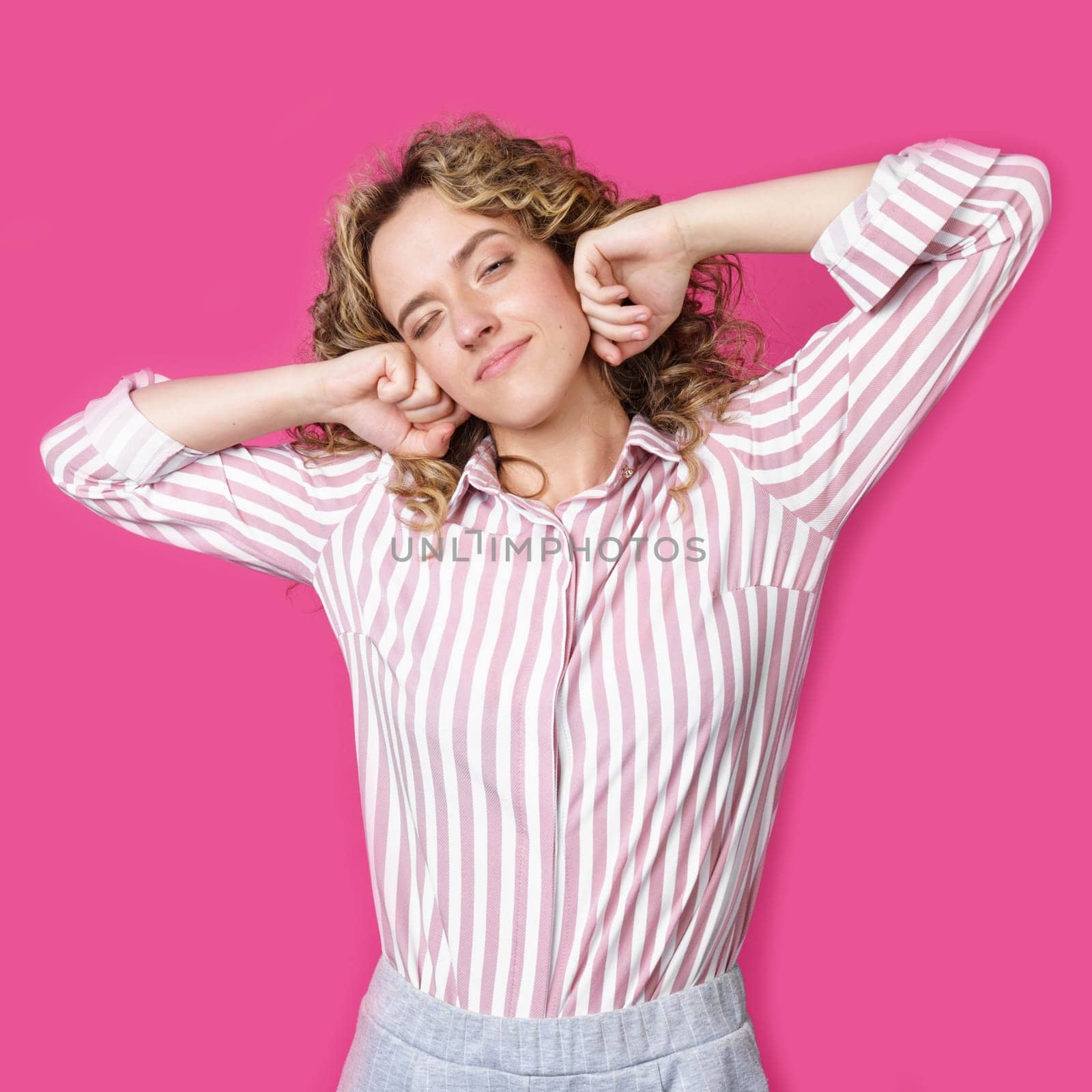 Young woman stretching out her hands after work. Isolated on pink background