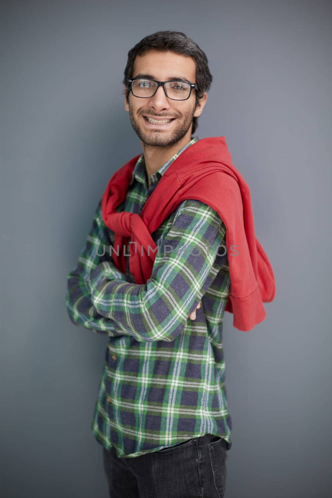 Smiling young unshaven business man posing against gray wall background studio portrait.