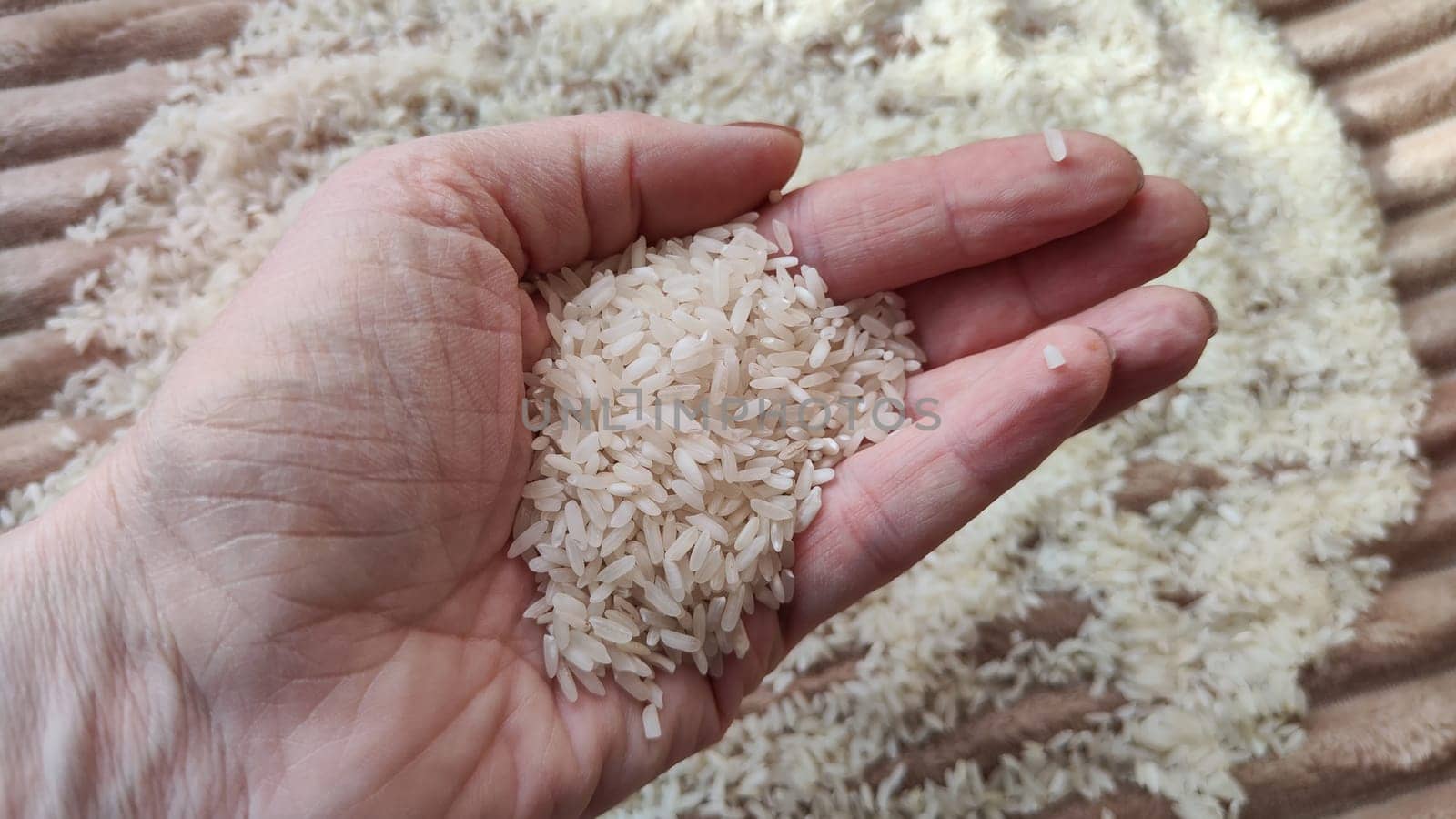 White cereals rice and hand of woman in it. Food for background and texture. Product and food that can be stored for a long time. Partial focus by keleny