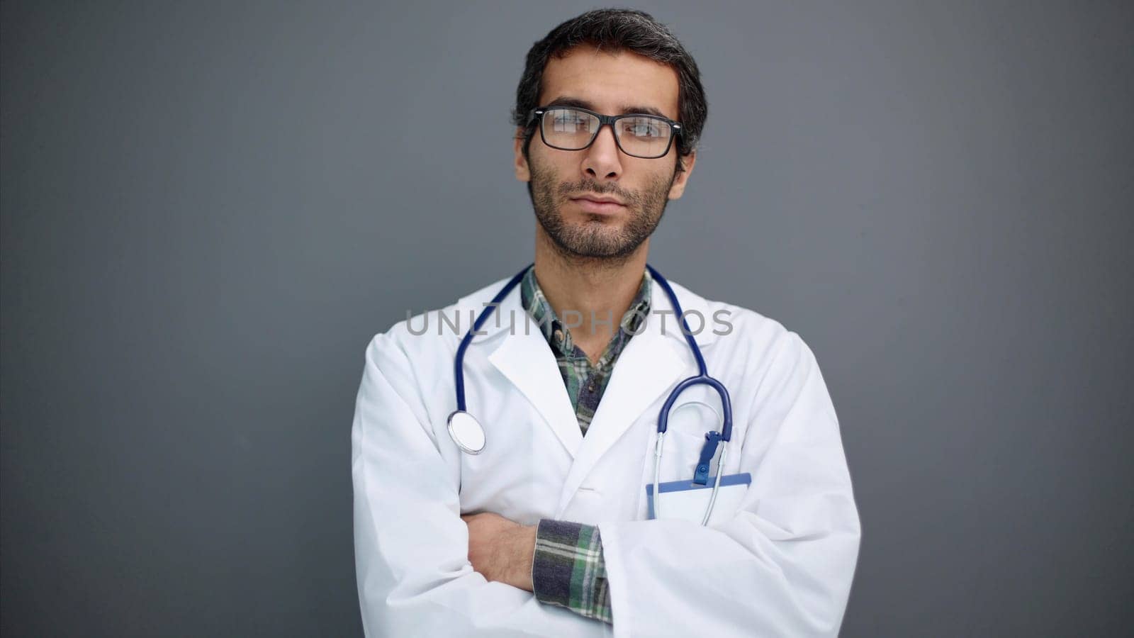 Close-up of a young male doctor in a white coat and round glasses isolated on a gray background by Prosto