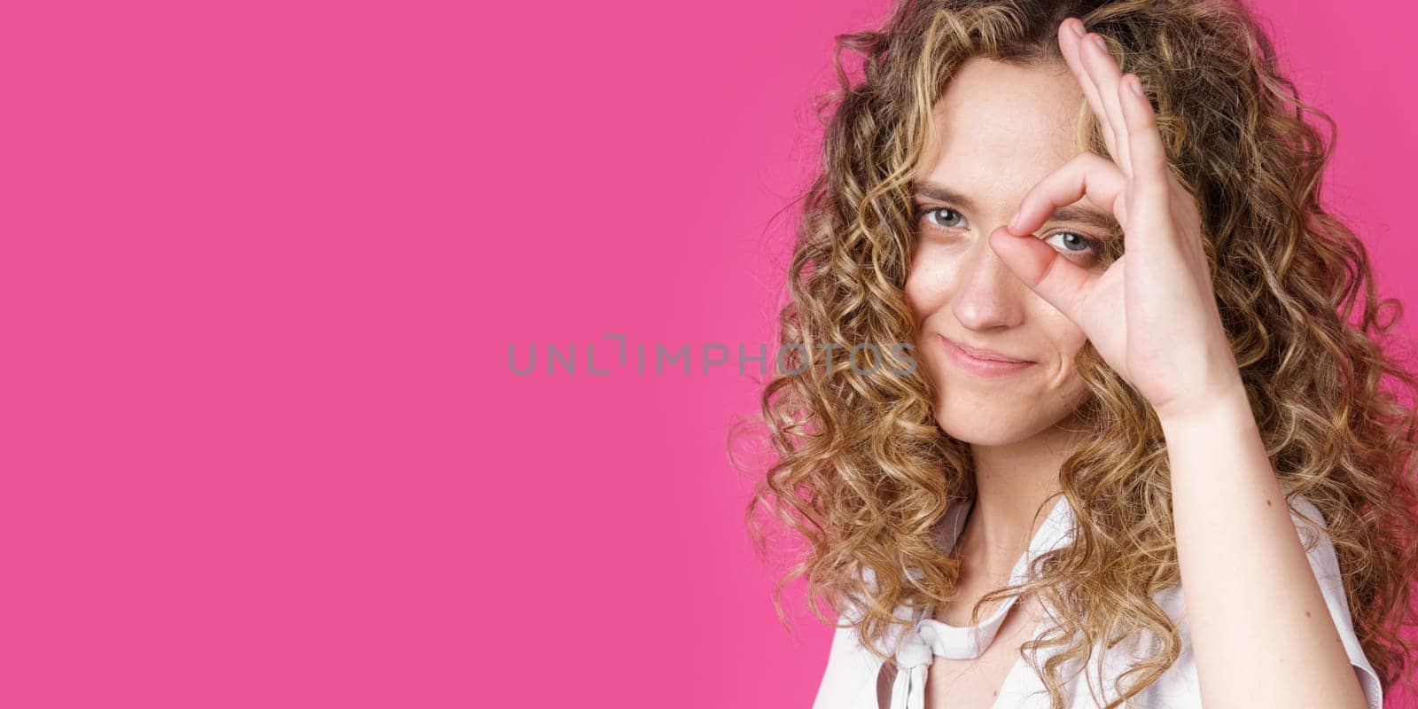 Portrait of a beautiful young woman makes a ok gesture, demonstrates agreement, loves an idea, smiles happily, models indoors. Well thank you. Hand sign