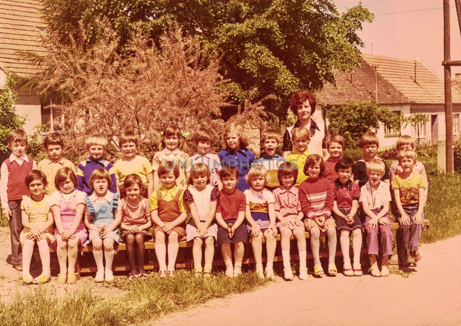 Retro photo shows pupils schoolmates and their female teacher. Color photo. by roman_nerud