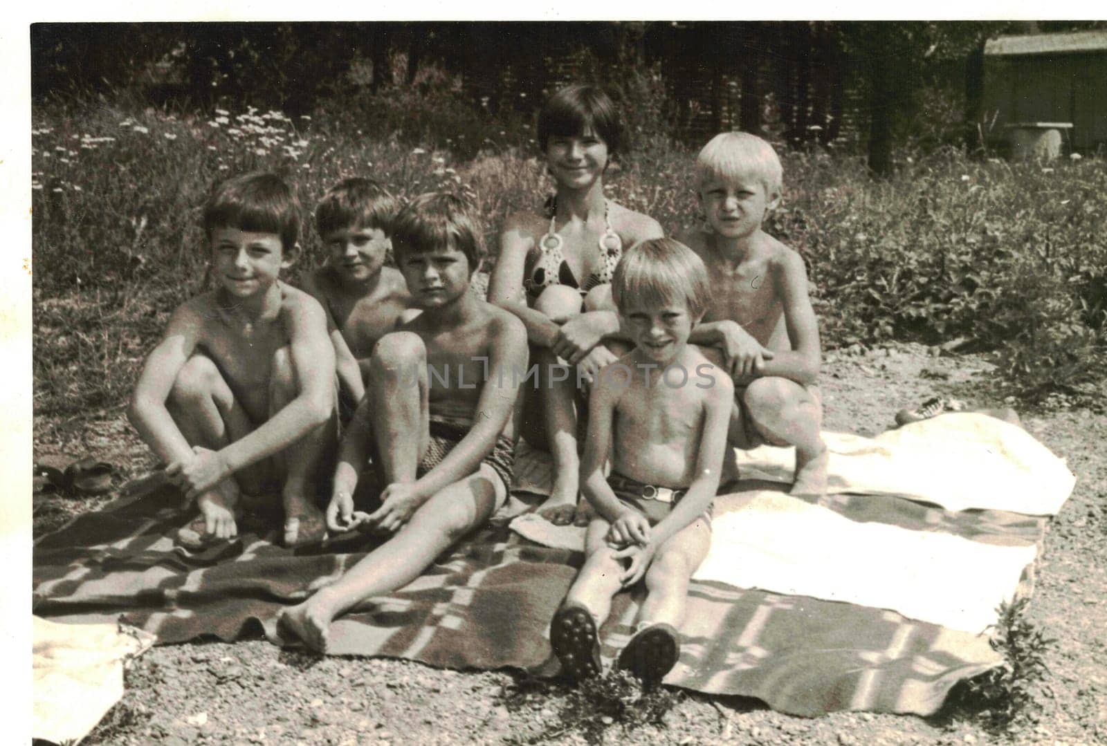 THE CZECHOSLOVAK SOCIALIST REPUBLIC - CIRCA 1980s: Retro photo shows children enjoy summertime. Kids sit on the blanket and take a sunbath