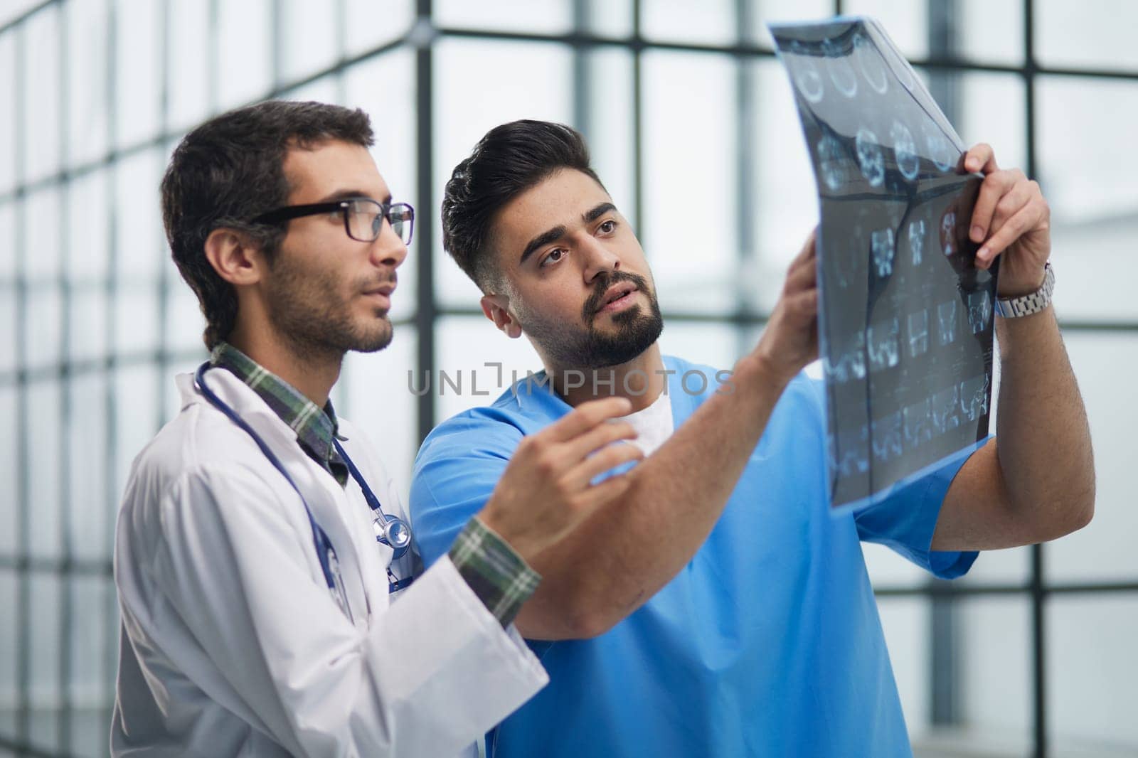 Male medics consult with each other while looking at x ray image.