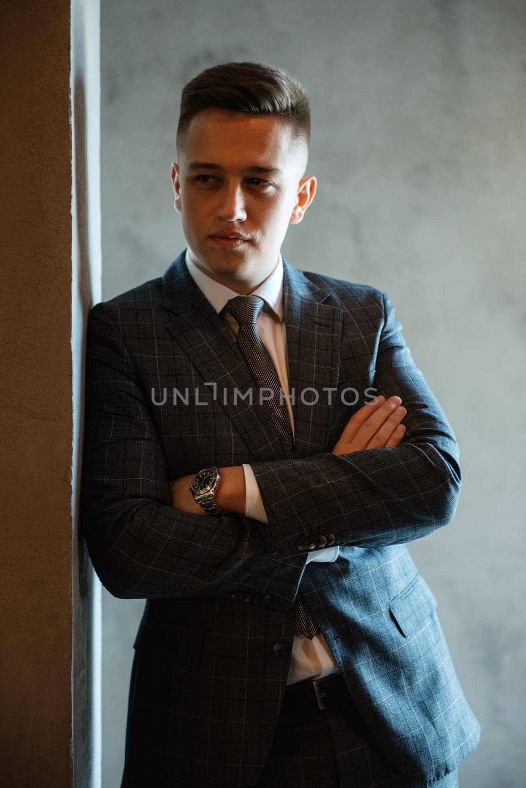 portrait of a groom in a gray plaid suit with a tie on the wedding day in a bar