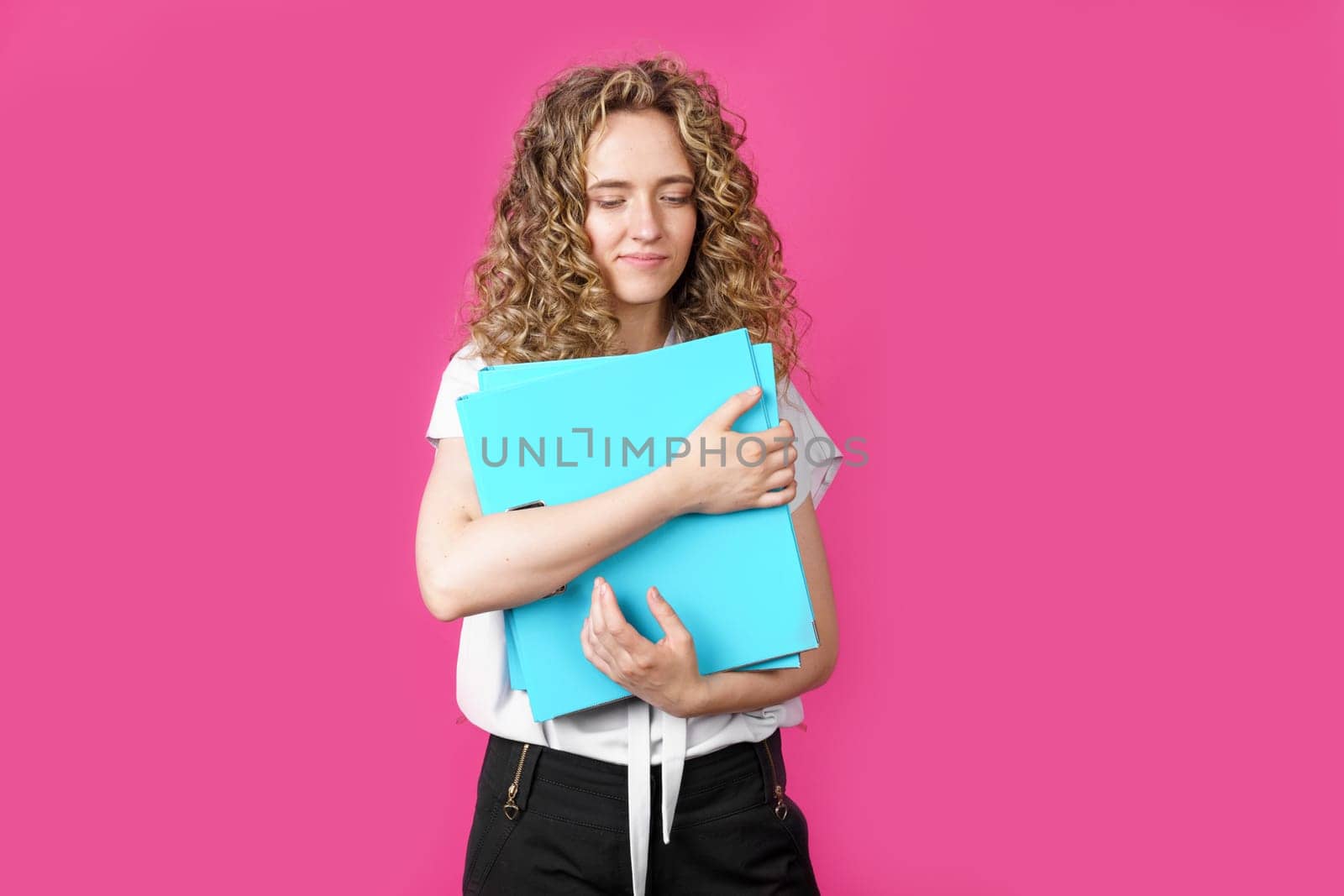 A young woman holds folders with documents in her hands. Isolated on pink background