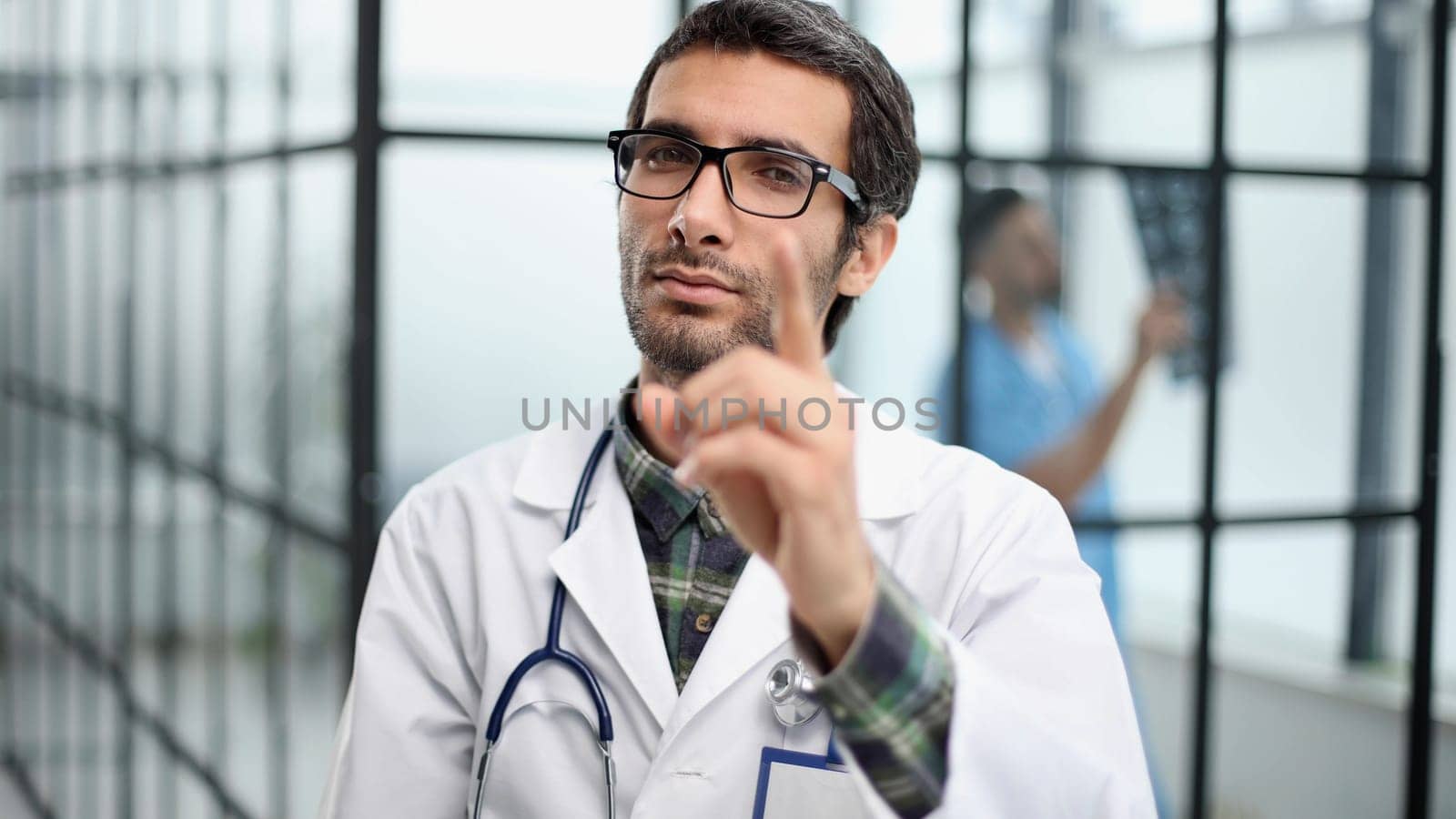 attentive doctor in a white coat pointing his finger at you while standing in the corridor of the hospital