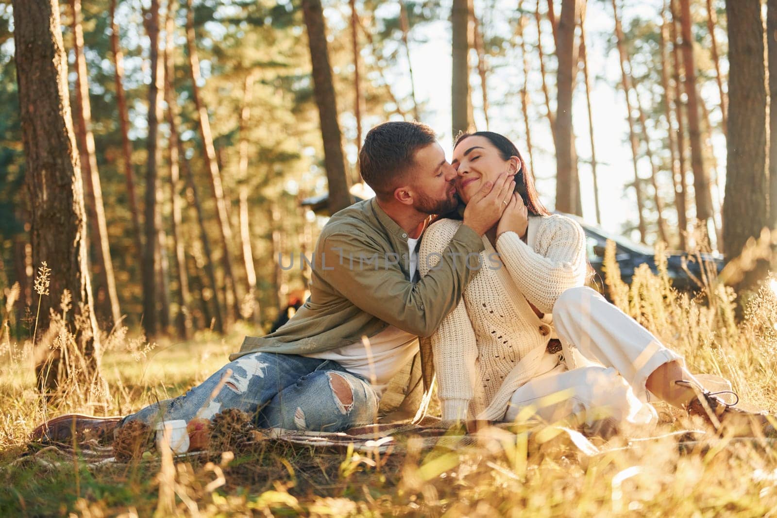 Happy couple sitting on the ground in the forest.