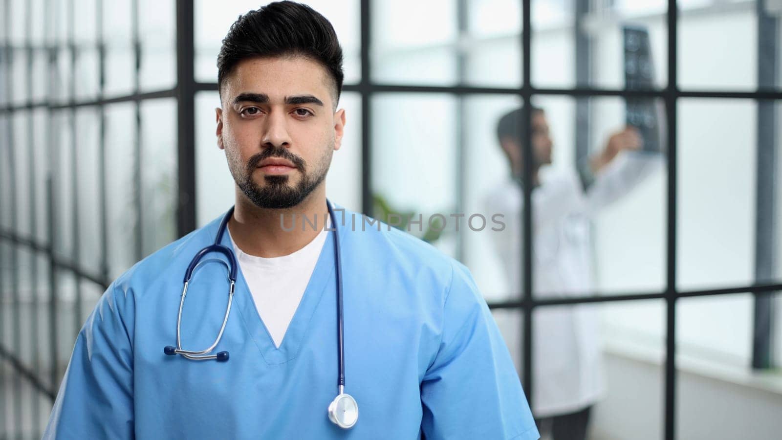 Cheerful mature doctor posing at camera, healthcare and medicine.