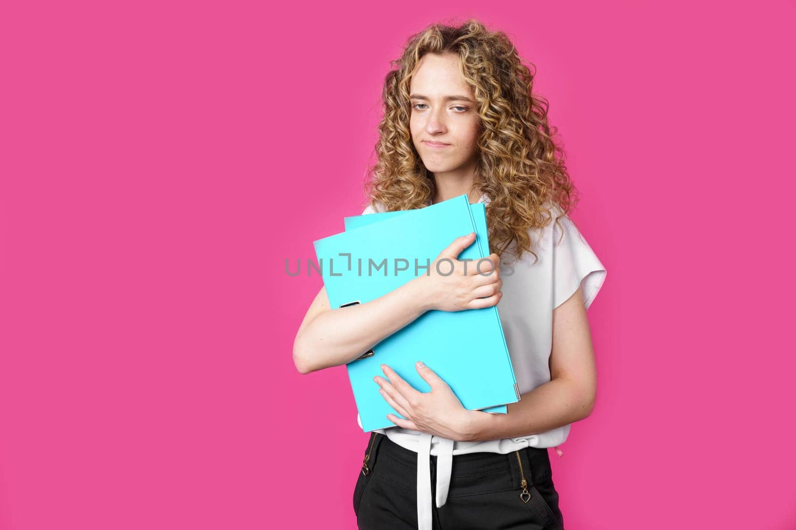 A young woman holds folders with documents in her hands. Isolated on pink background