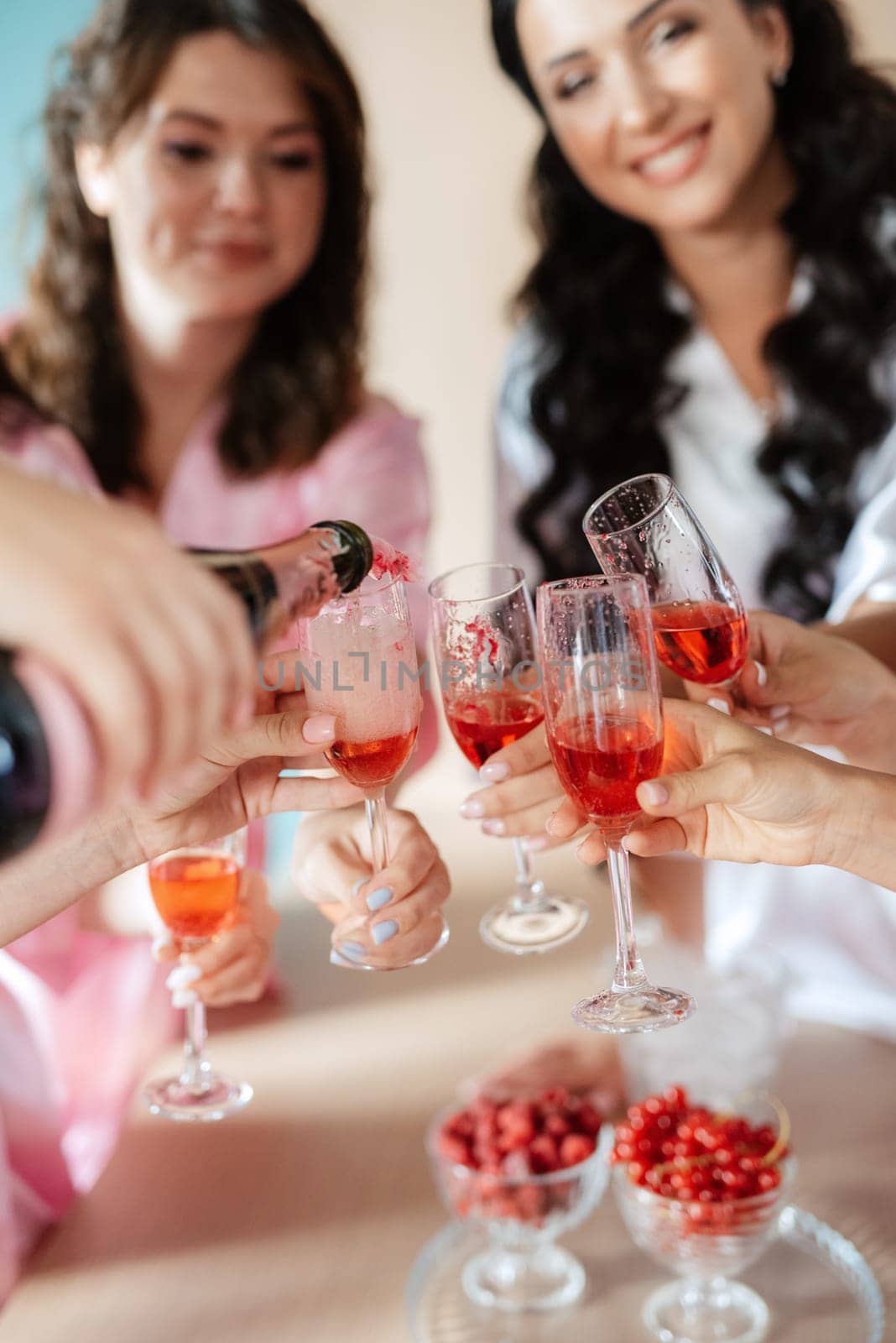bride with bridesmaids in silk pajamas in the kitchen drinking pink champagne by Andreua