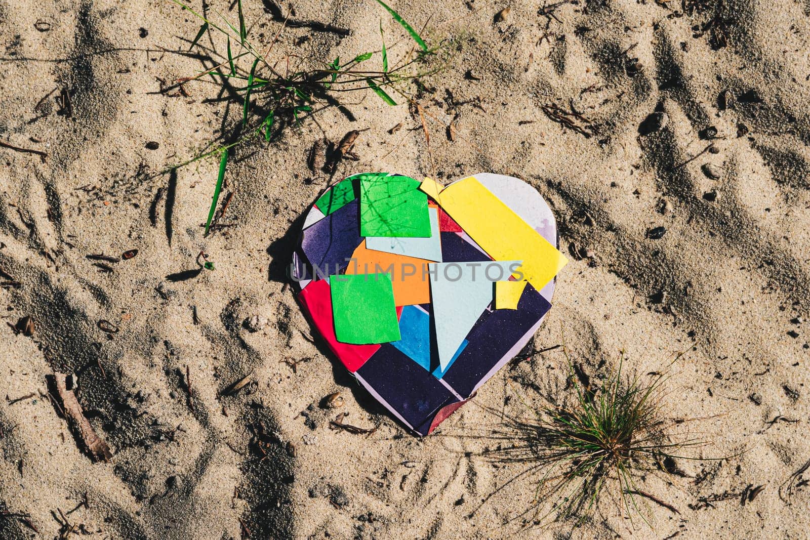 A heart made of colored squares sits in the sand