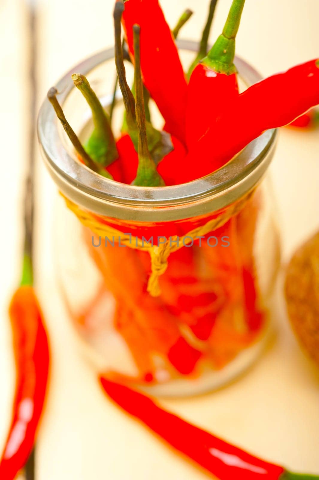 red chili peppers on a glass jar over white wood rustic table