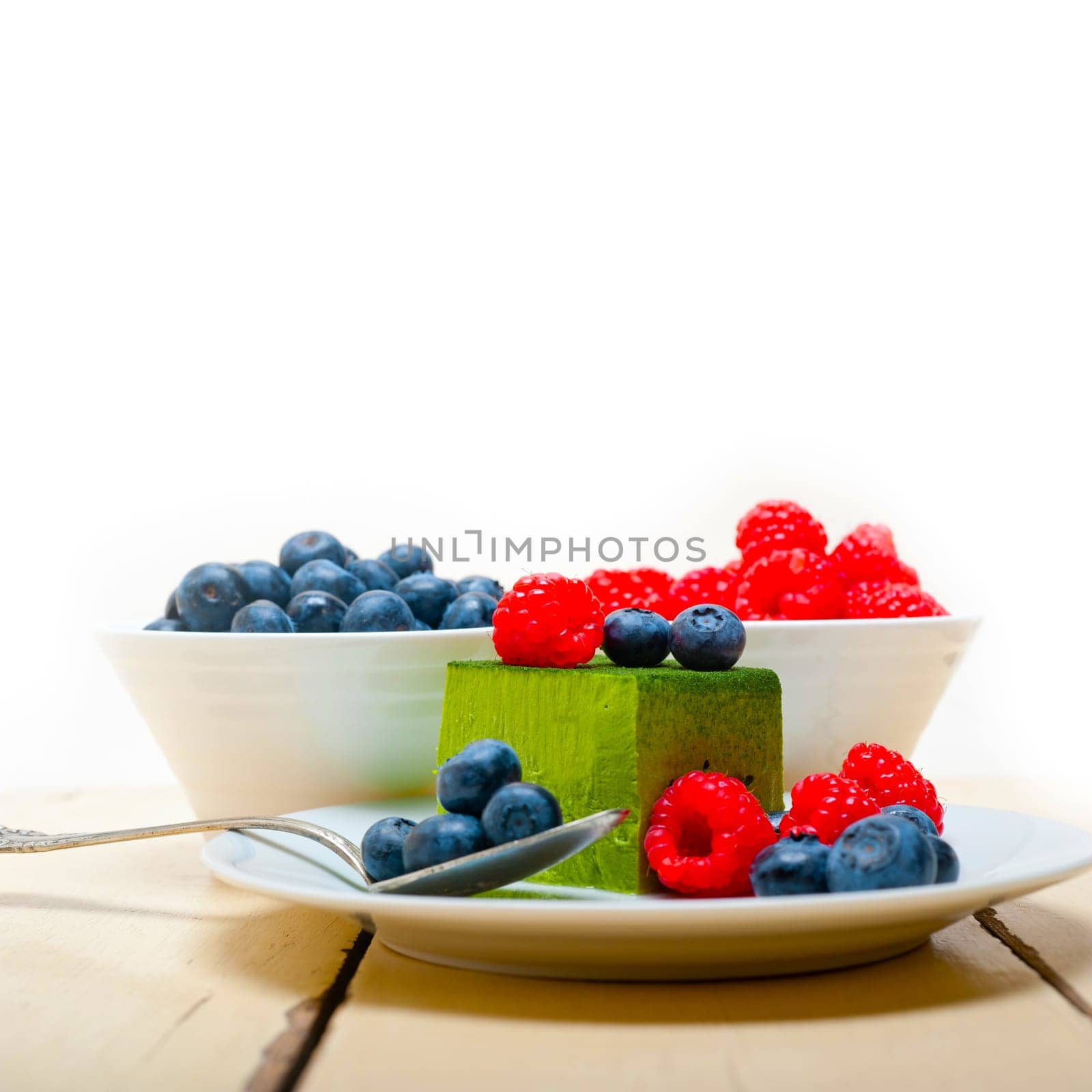 green tea matcha mousse cake with raspberries and blueberries on top