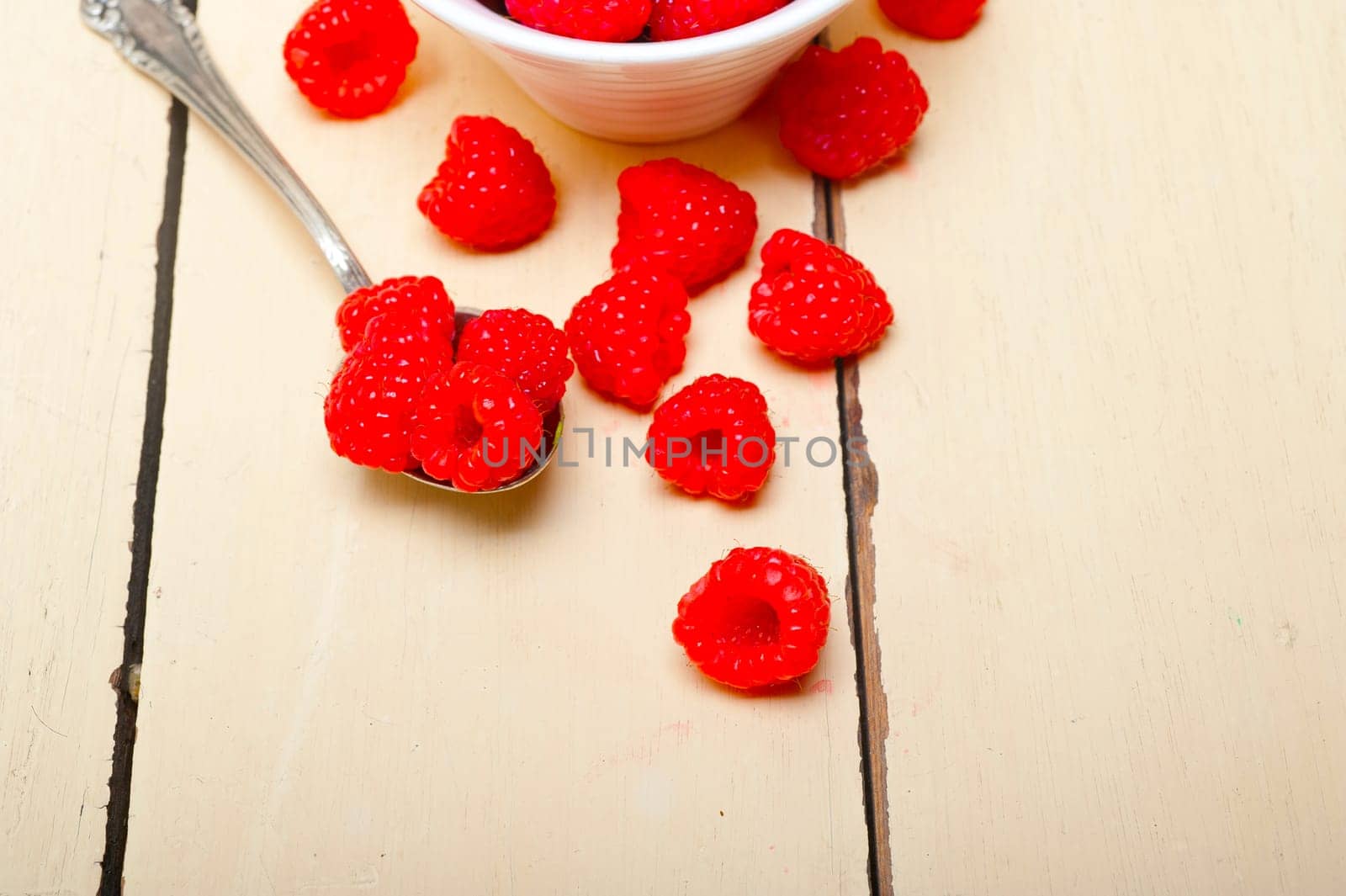 bunch of fresh raspberry on a bowl and white table by keko64