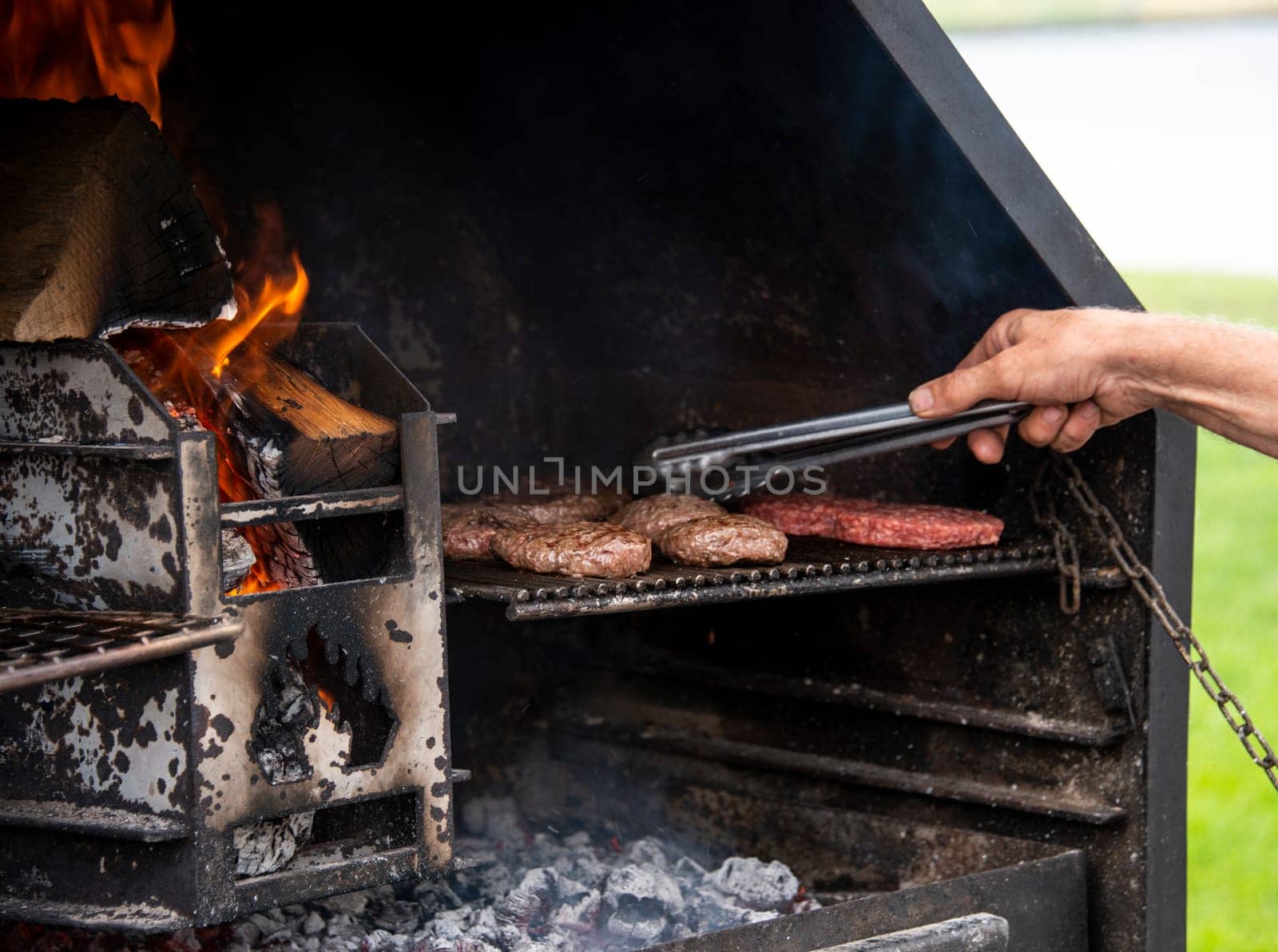 a man is busy turning the burgers on a barbecue over an open fire