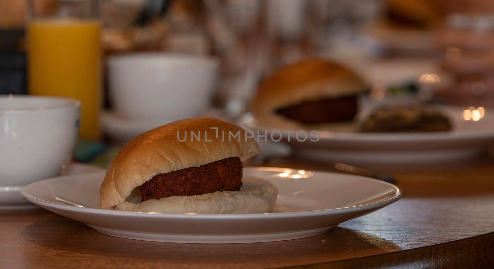 Traditional white bun with a Dutch kroket , called broodje kroket on a lunch table