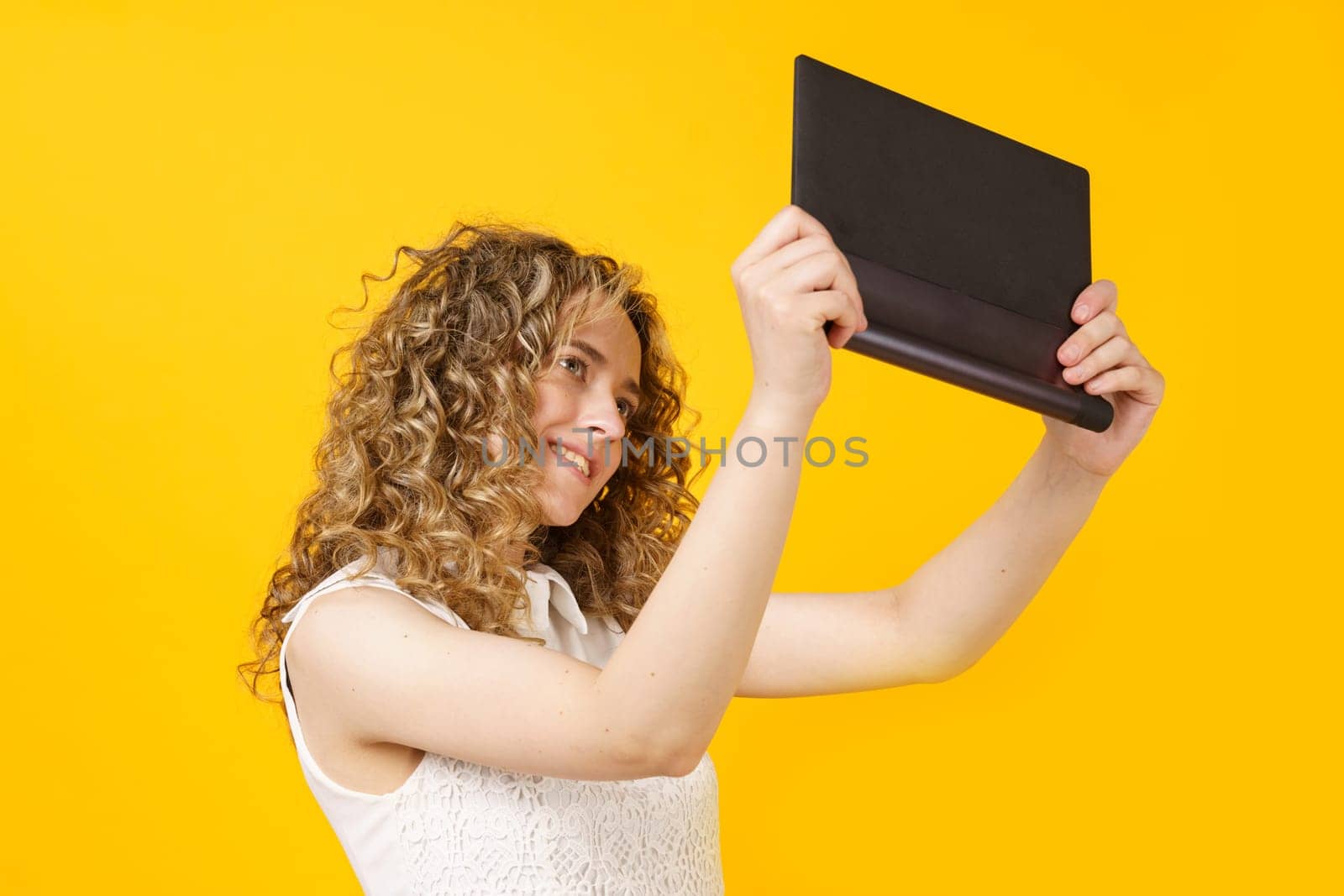 Portrait of a young woman who communicates on a tablet. Female portrait. Isolated on yellow background